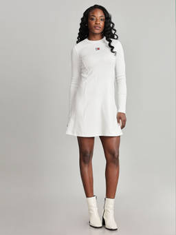 Woman wearing a white ribbed knit mini dress and white ankle boots