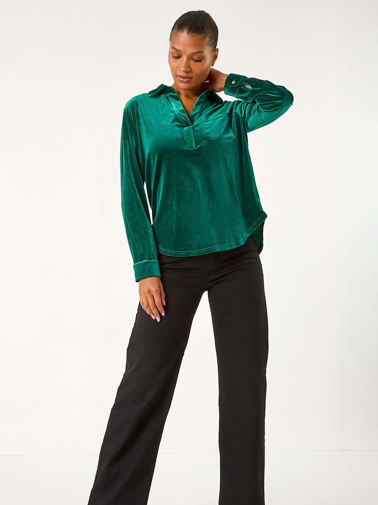 Emerald green velvet popover top with black wide-leg trousers