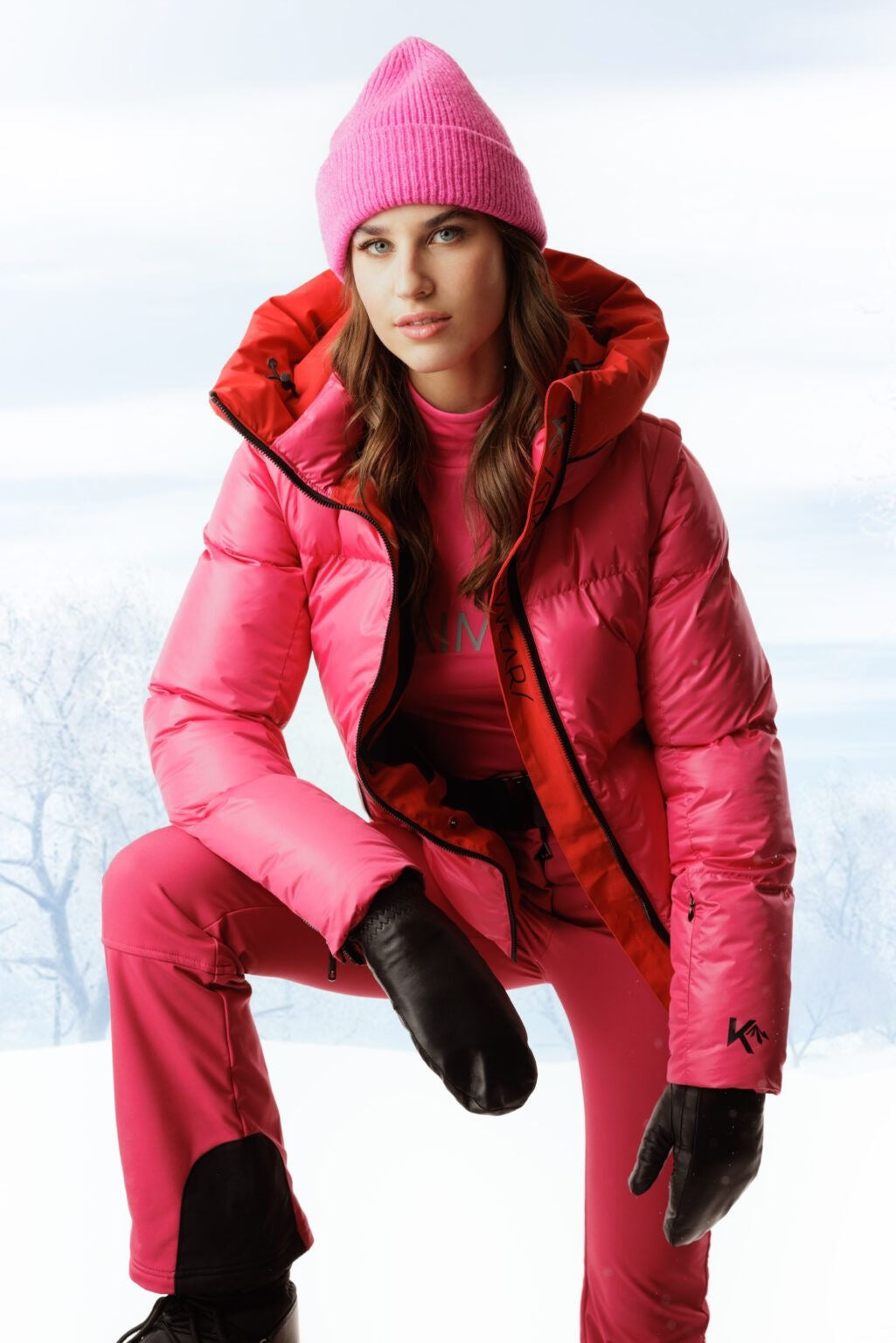 Woman wearing a pink puffer jacket with ski-ready winter layers