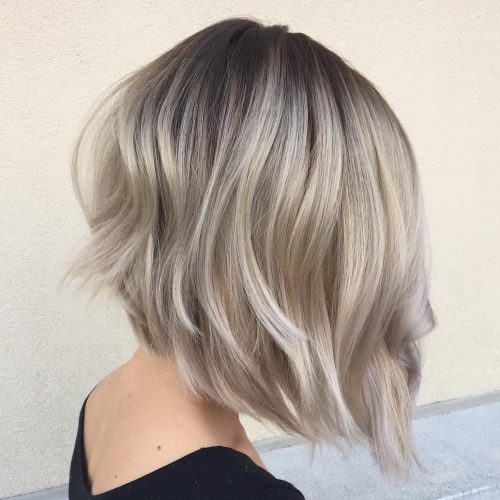 Back view of an angled ash-blonde bob with dark roots