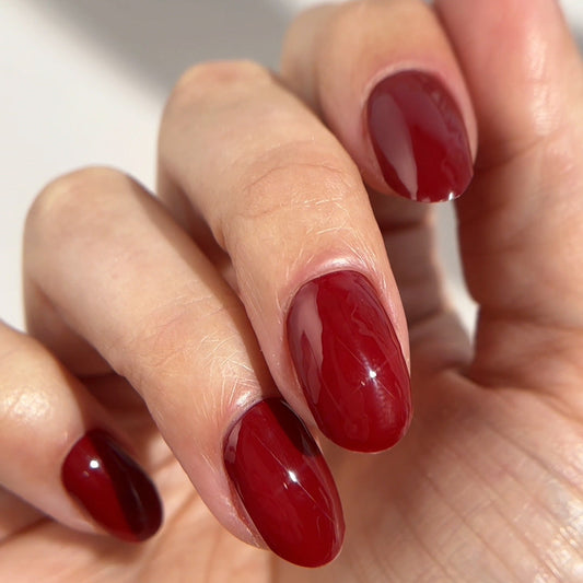 Glossy cranberry-red oval nails in a close-up hand shot