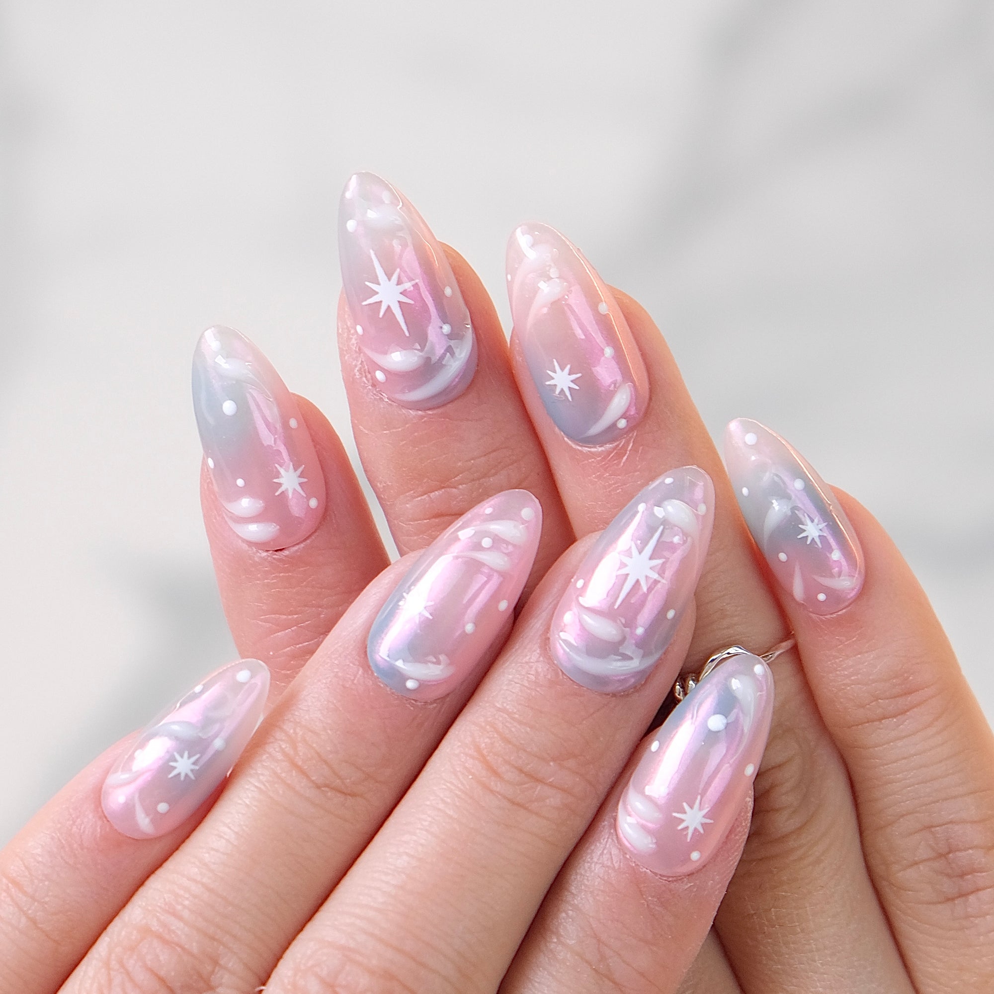 Iridescent aurora almond nails with white starburst art and micro dots
