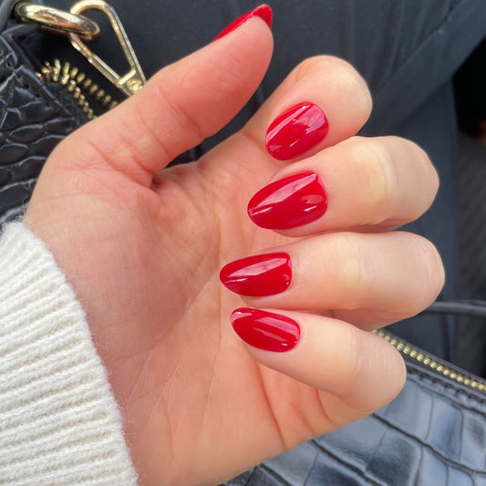 Short round nails painted in a glossy, vibrant cherry red