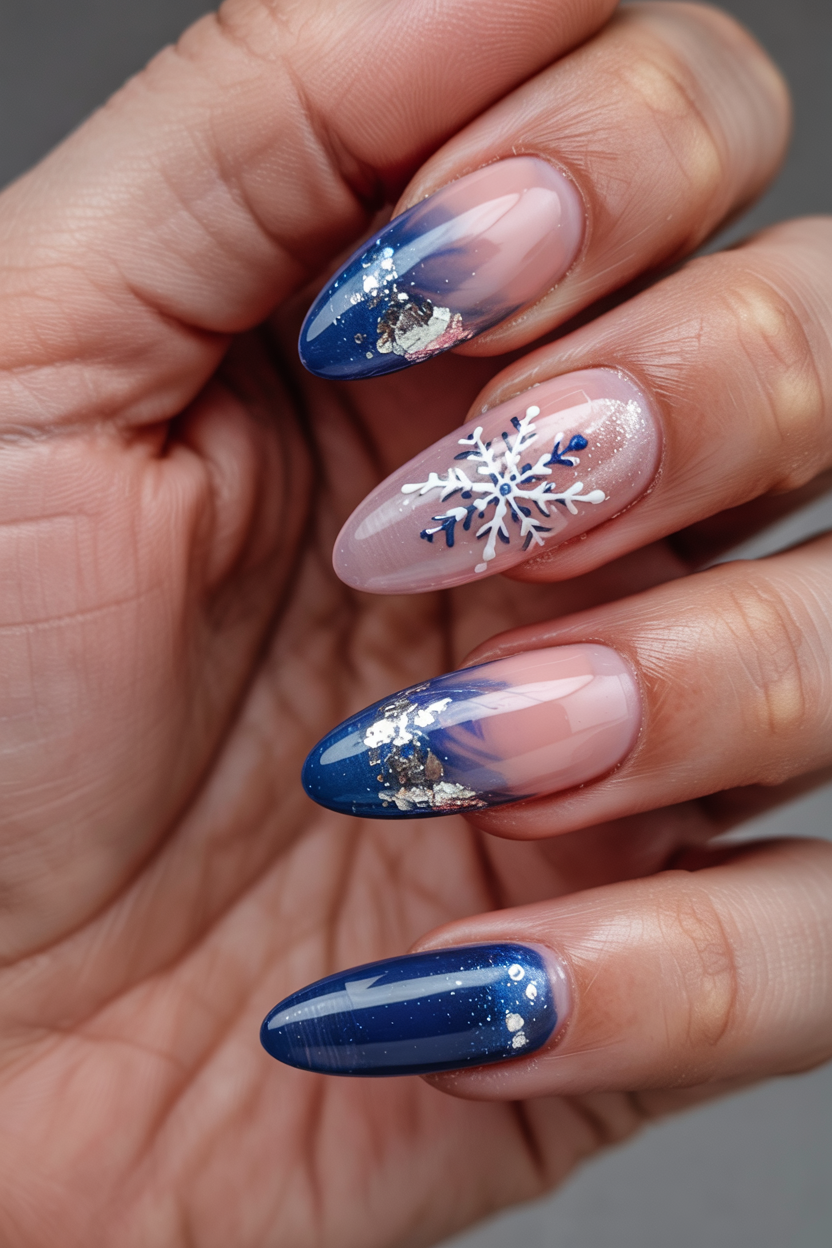 Medium almond nails with a blue ombre gradient and white snowflake accent
