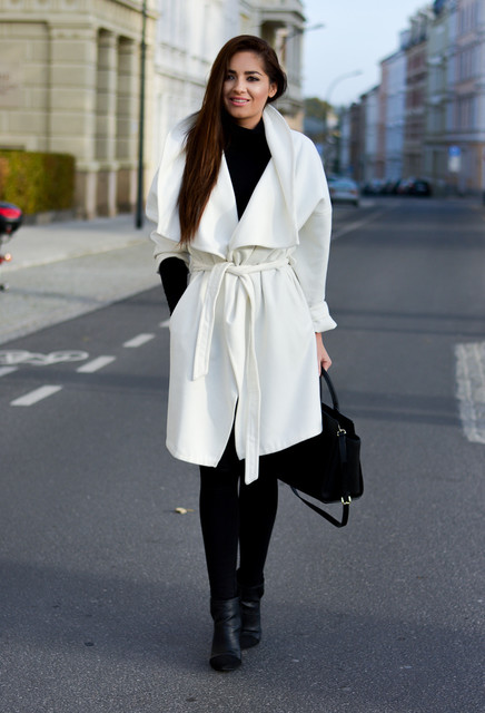 Woman wearing a white wrap coat over an all-black winter outfit