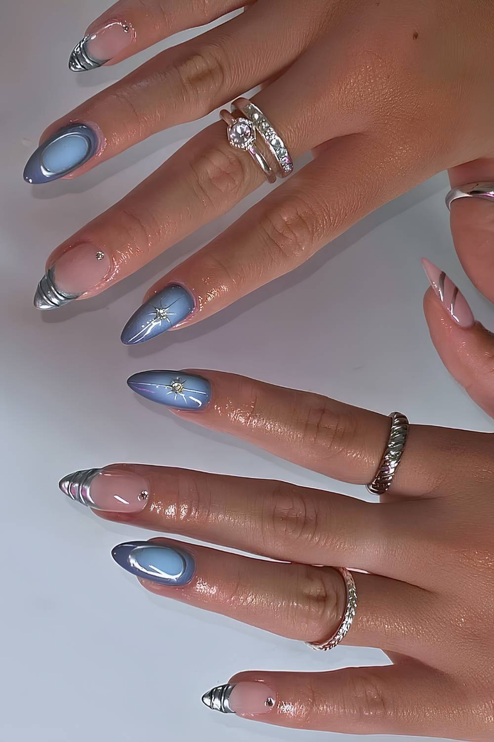 Long almond nails in periwinkle blue chrome with starburst art, mixed with nude nails with silver chrome French tips