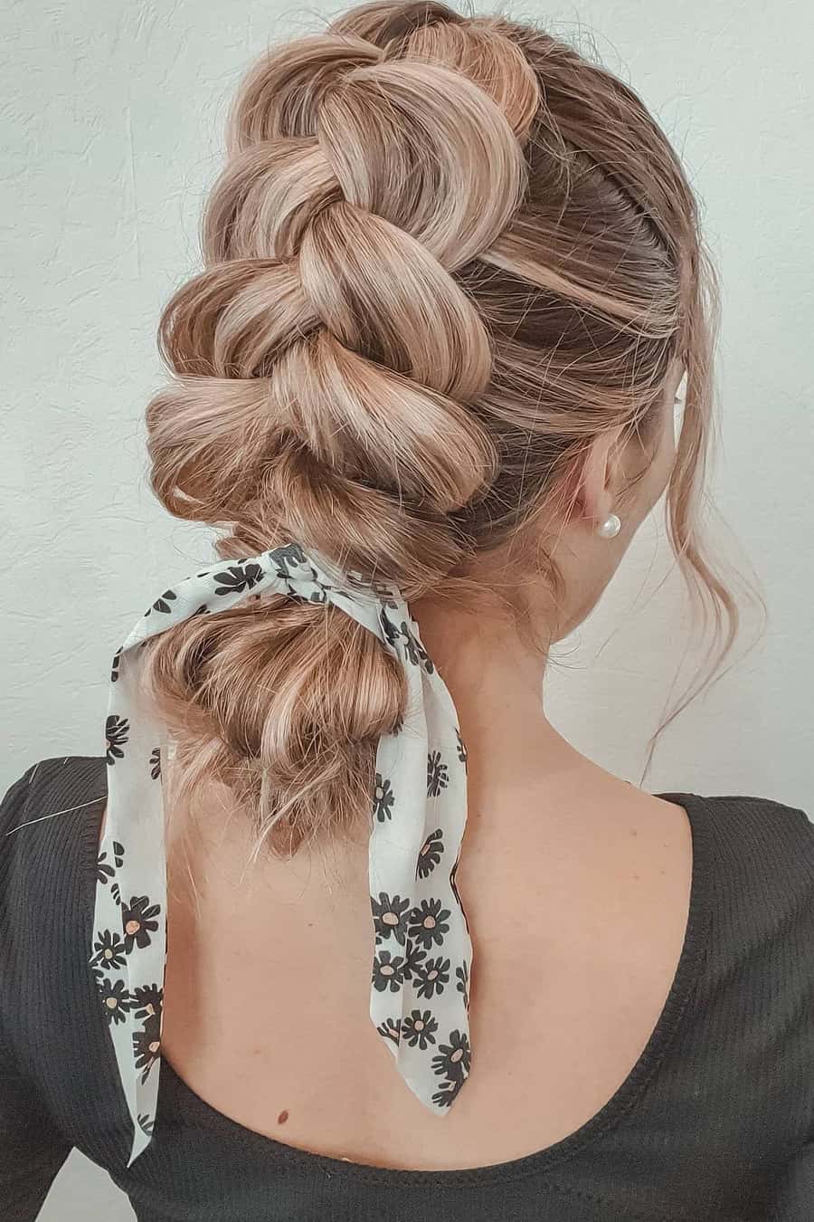 Chunky blonde braid finished with a white and black floral scarf tied at the end