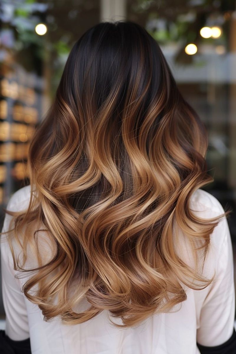 Back view of long wavy hair with dark roots melting into golden bronze ends, center part