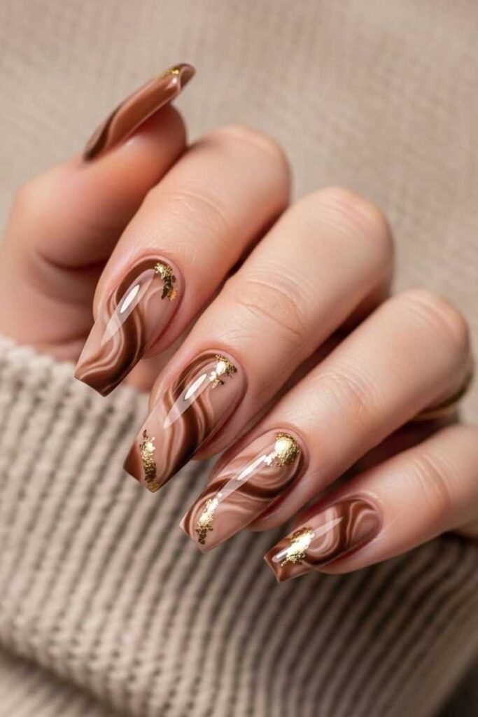 Long coffin nails in glossy chocolate brown with swirling gold foil marble waves