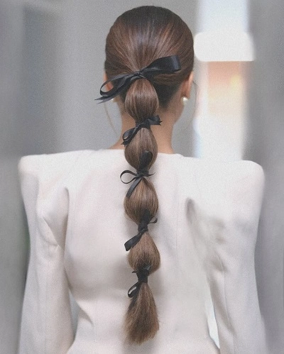 Long brunette hair in a bubble ponytail tied with small black satin ribbon bows
