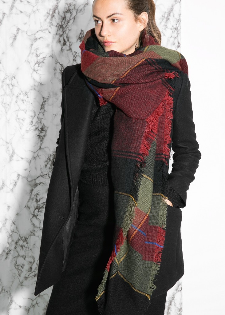 Woman in a black coat with an oversized red and green plaid scarf