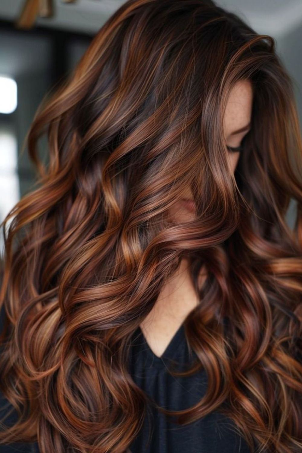 Three-quarter view of long wavy hair with chestnut roots melting into auburn-copper ends