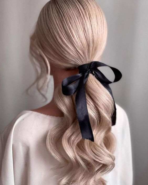 A low ponytail finished with an oversized black velvet bow