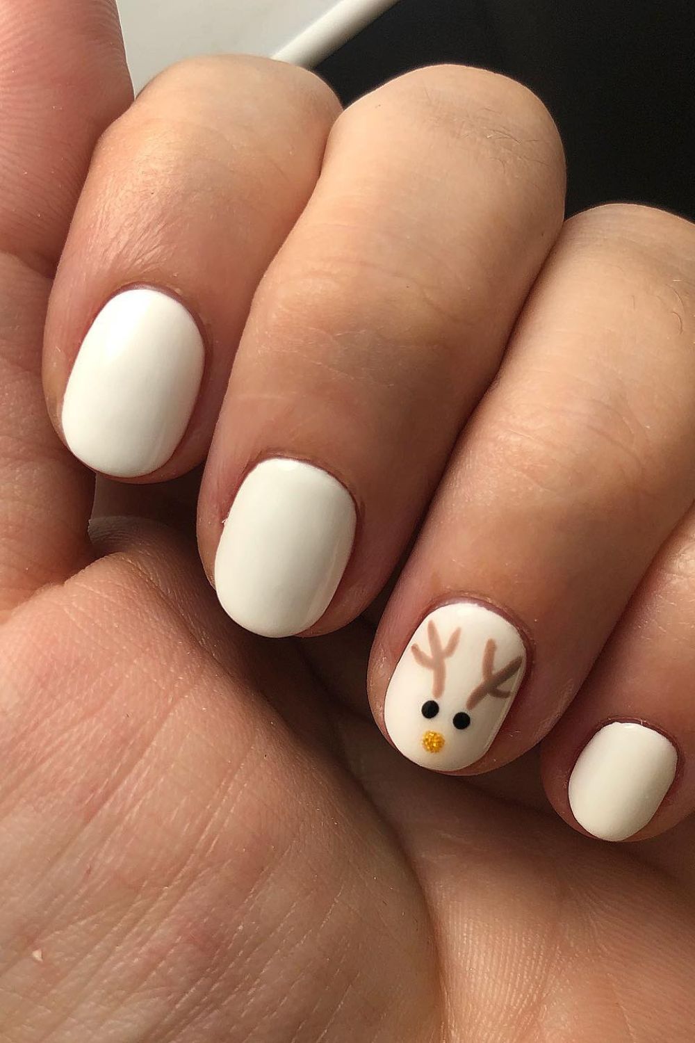 Matte white short nails with a hand-painted reindeer face on the ring finger.