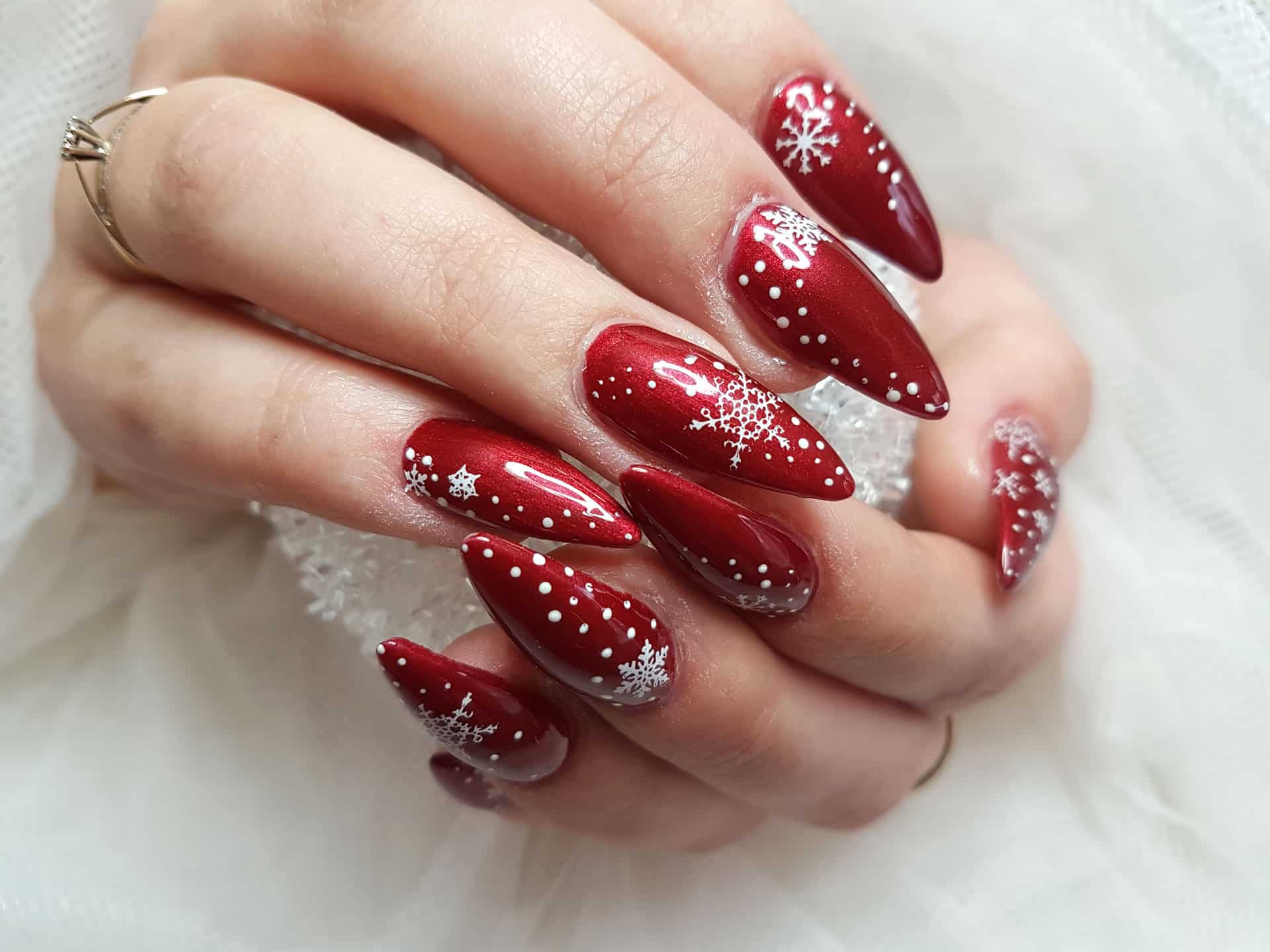 Metallic cranberry red stiletto nails with white snowflake and dot art