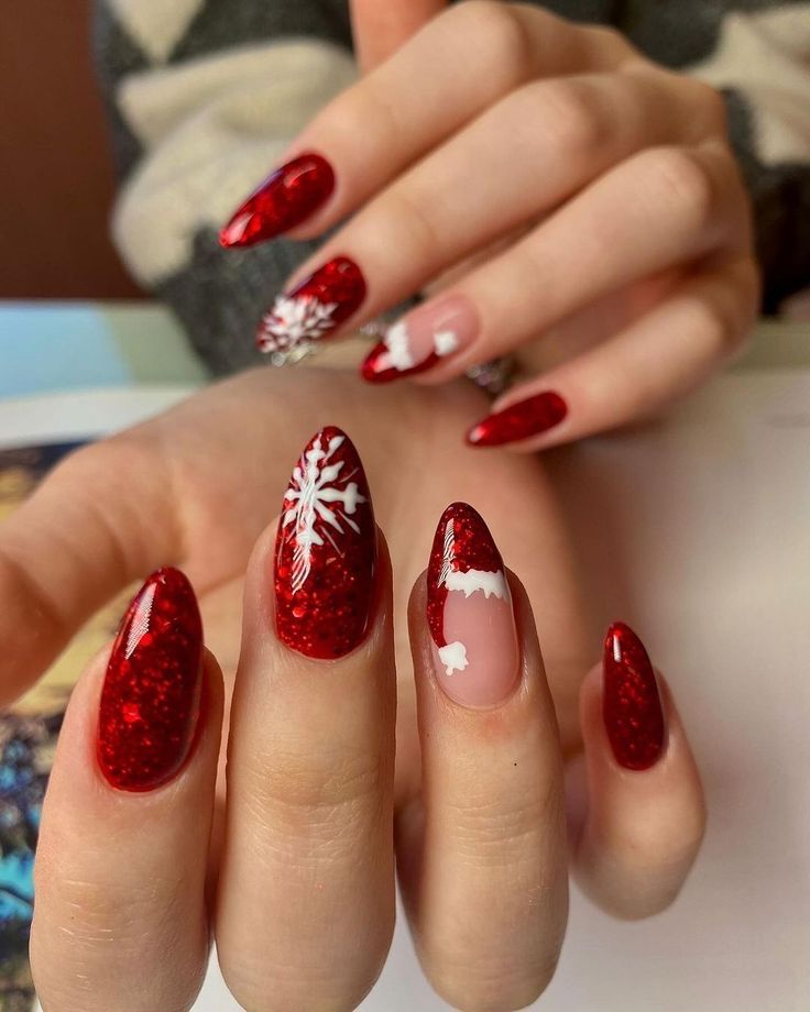 Medium almond nails in cherry-red glitter with white snowflakes and a Santa-hat accent nail