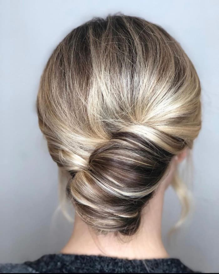 Rear view of a smooth classic French twist with blended dark-blonde and light-blonde tones.