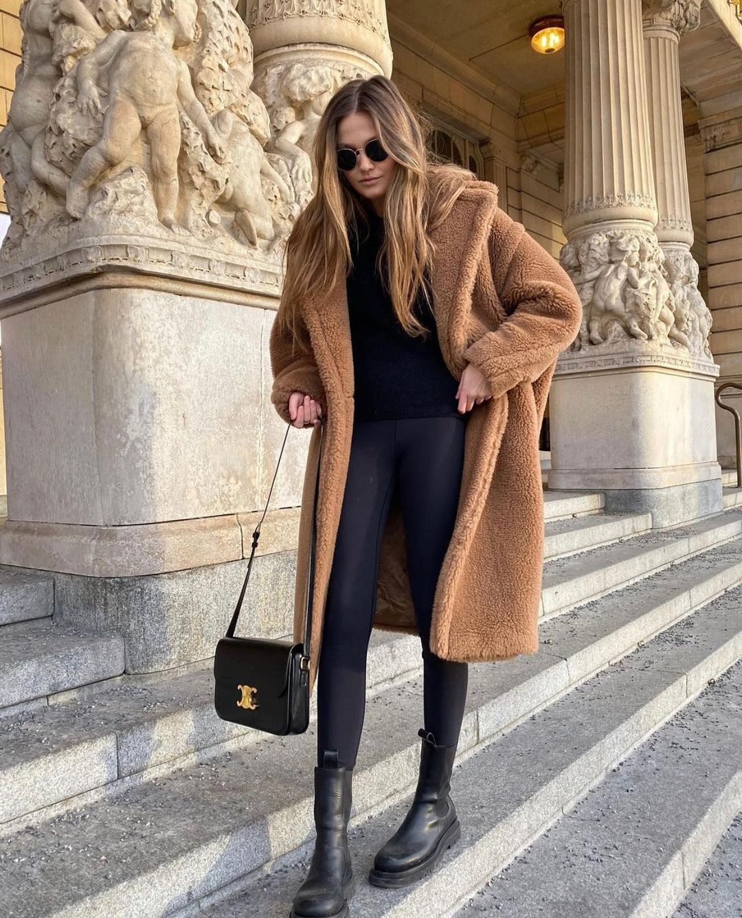 Woman wearing a teddy faux-fur coat with black leggings, a sweater and combat boots