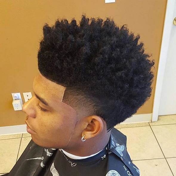 Tapered haircut with sponge-defined curls on top and a clean lineup