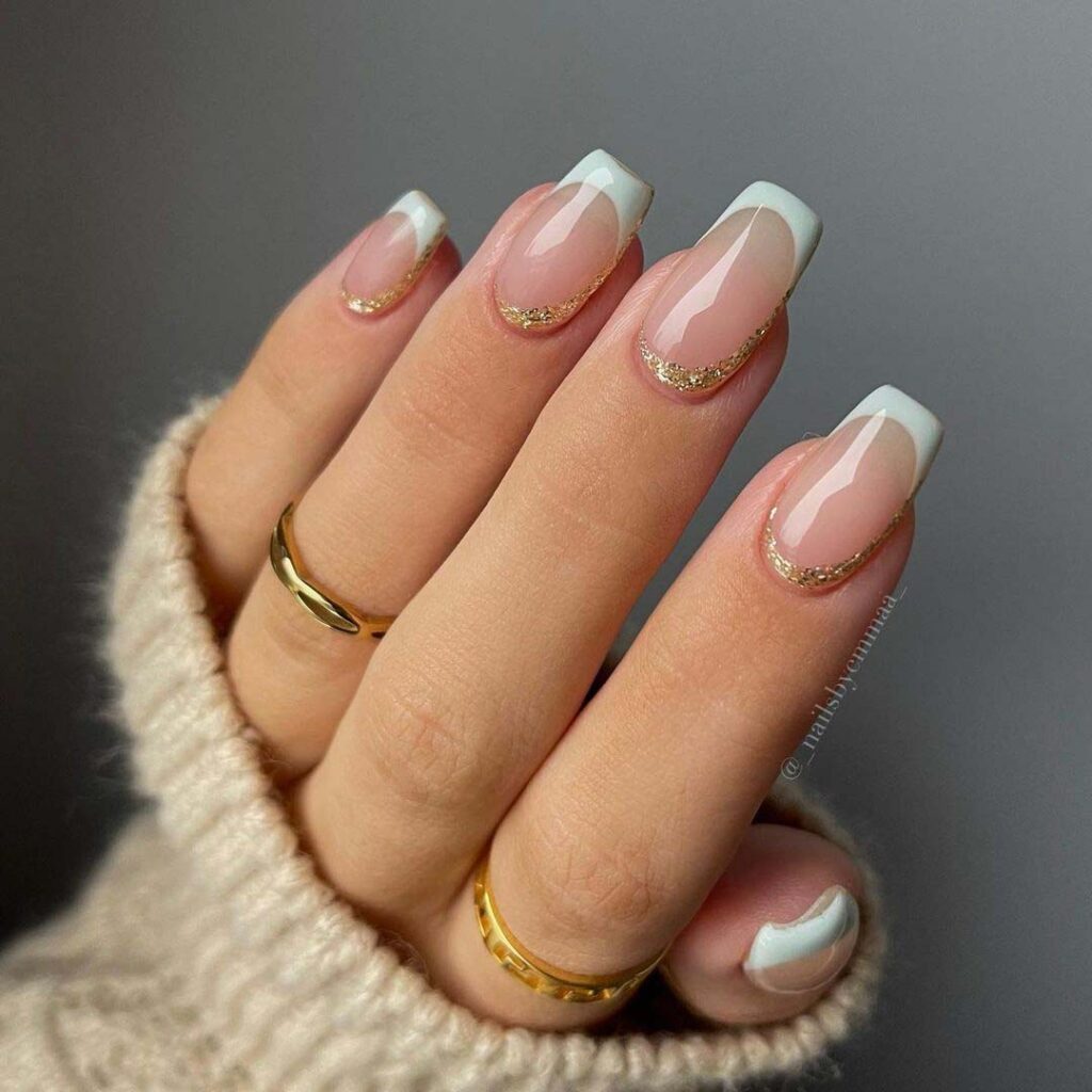 Sheer nude oval nails with gold glitter Christmas accents
