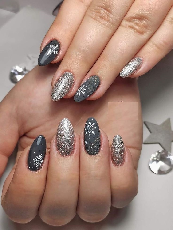 Dark charcoal gray almond nails with hand-painted white snowflakes, falling-snow dots and silver glitter accents