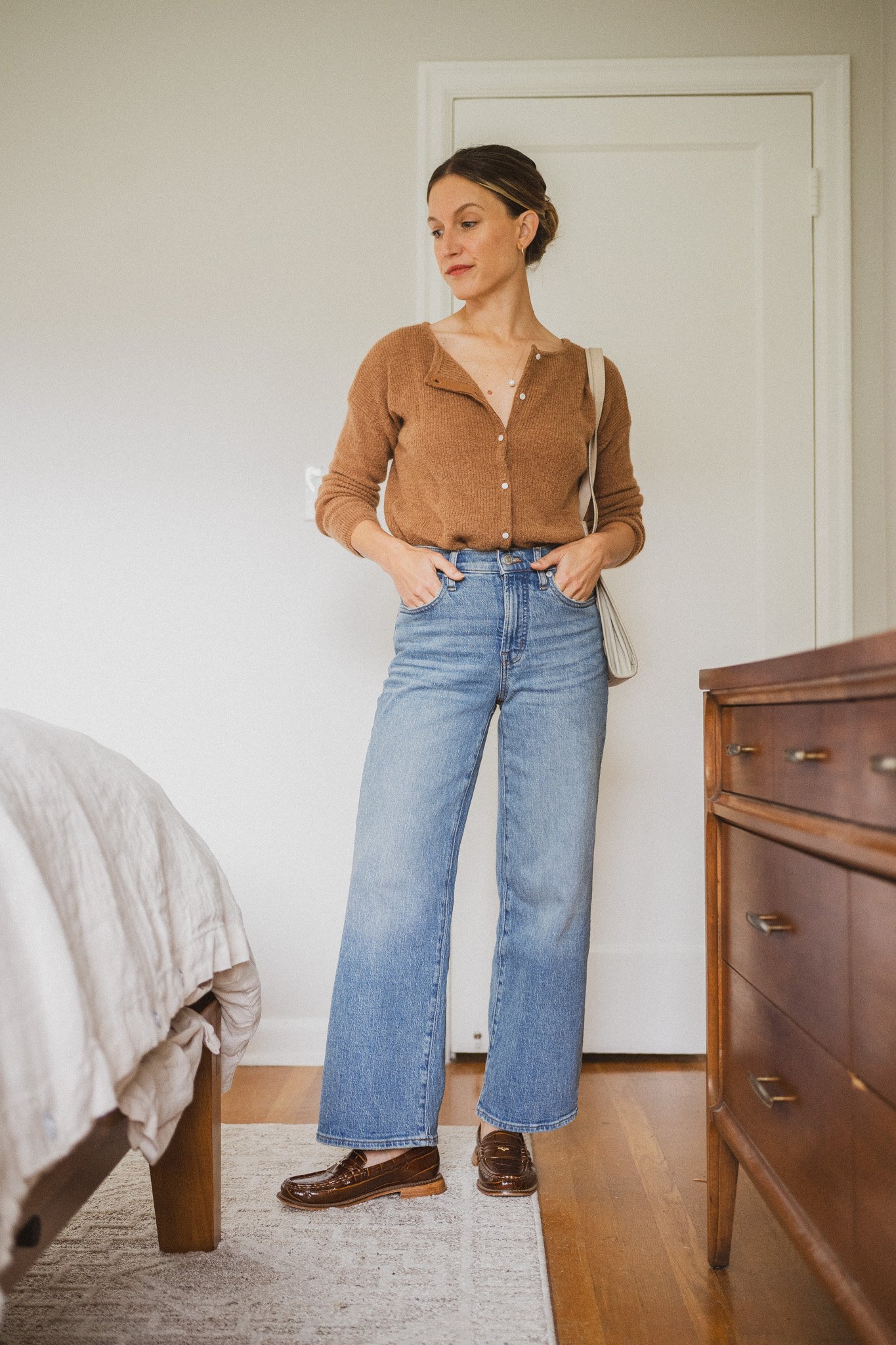 Woman wearing a caramel henley cardigan with wide-leg light-wash jeans and brown loafers