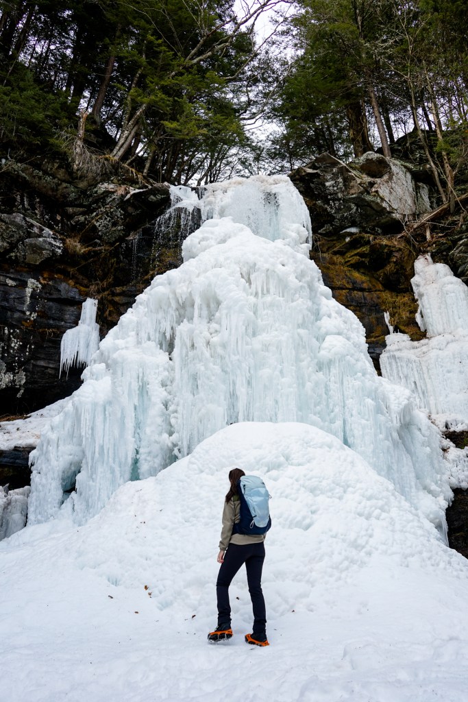 Woman in full winter hiking layers on a snowy forest trail in New York