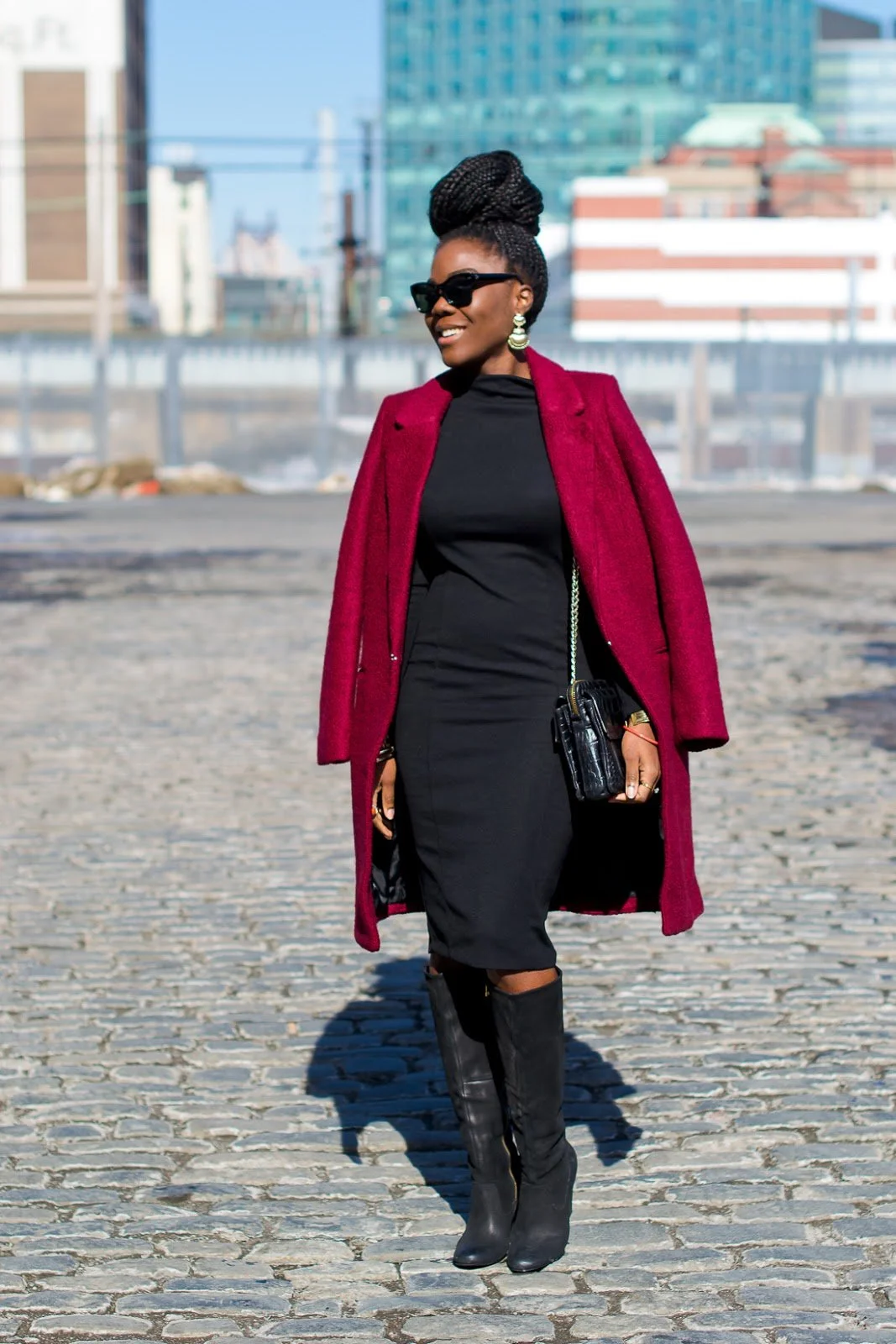 Woman in a burgundy-red wool coat over a black bodycon midi dress with black knee-high boots