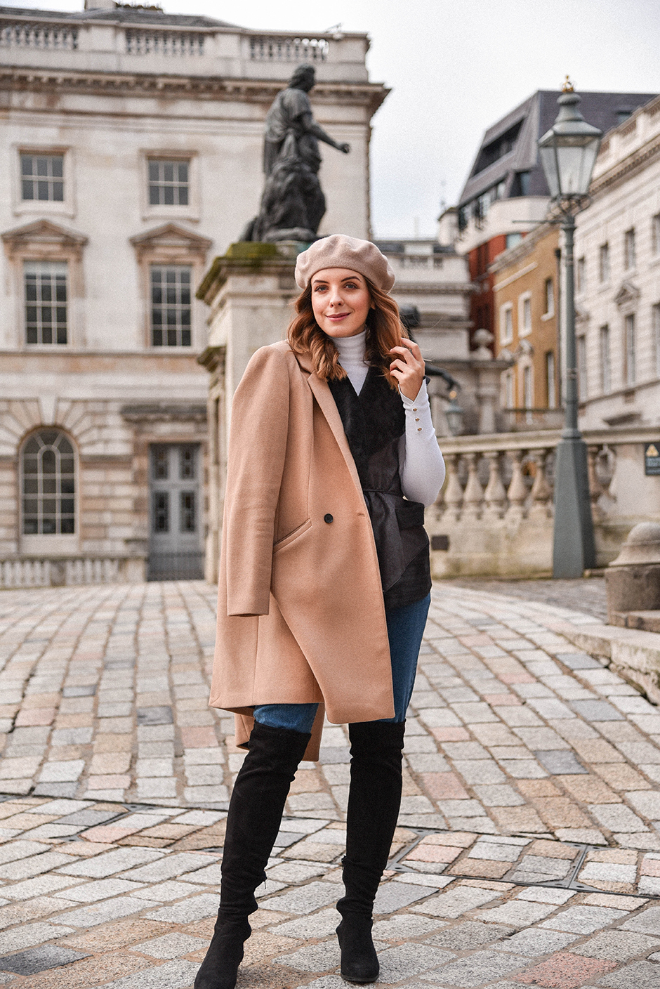 Woman wearing a beige beret with a camel coat and over-the-knee boots