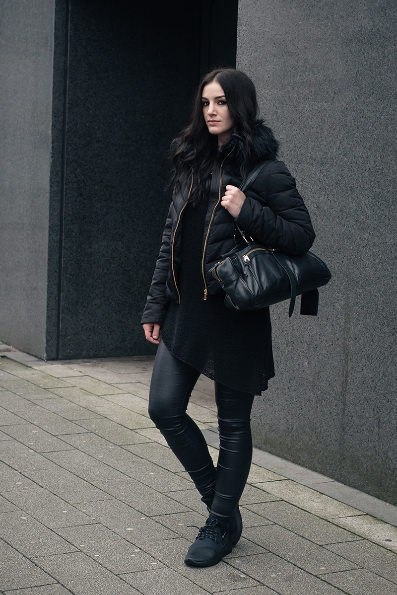 Woman in an all-black winter outfit with a padded jacket