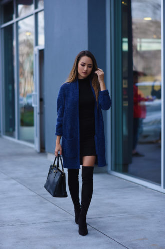 Black mini dress with a cobalt blue long cardigan and black over-the-knee boots