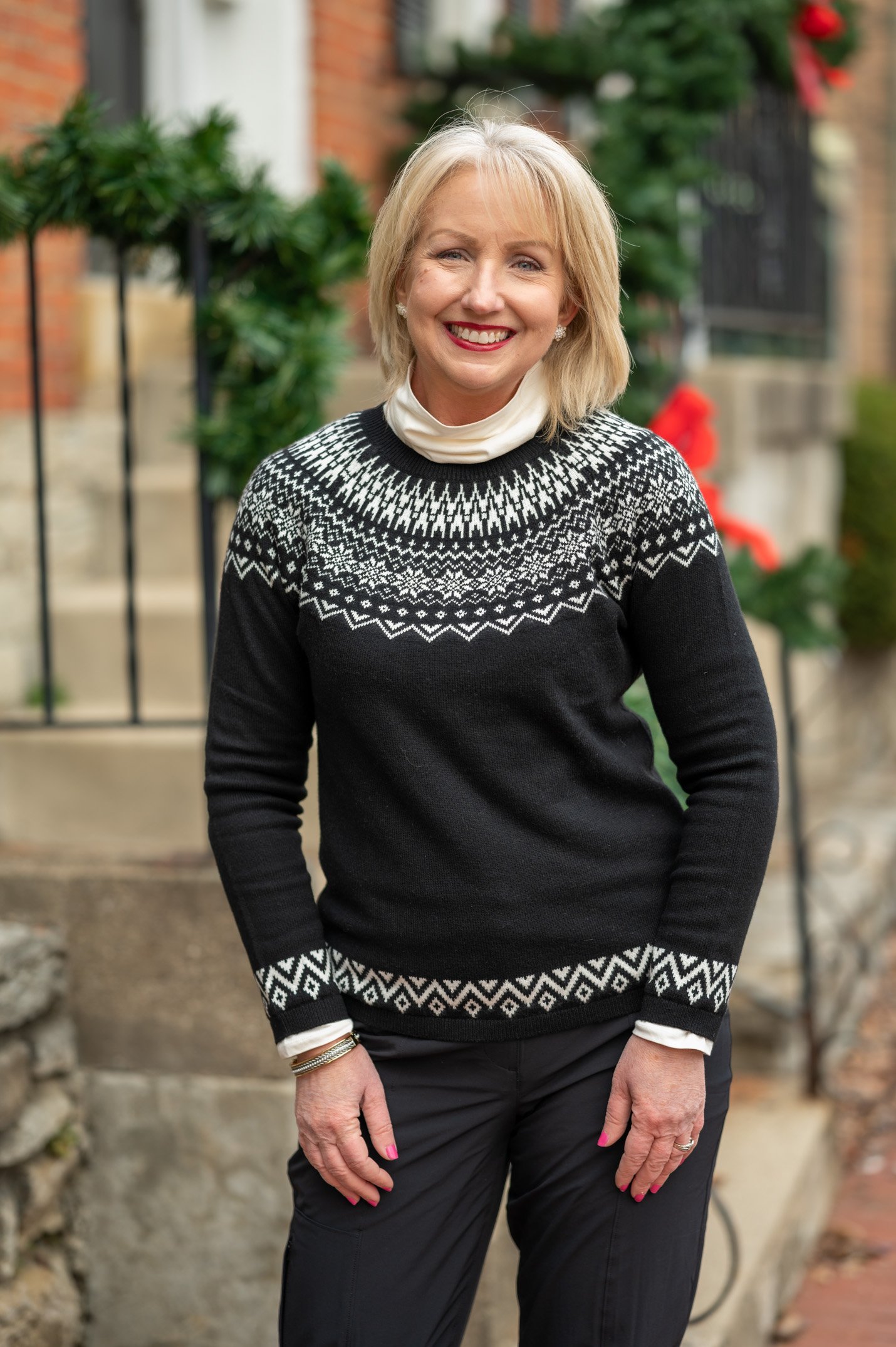 Woman wearing a black fair-isle yoke sweater layered over a white turtleneck