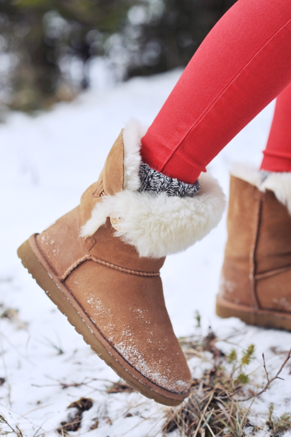 Close-up of tan fur-trim winter boots with red leggings and knit socks in the snow