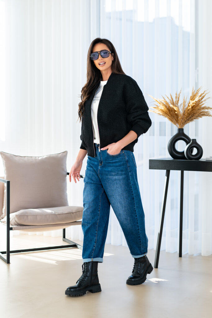 Woman in a black bomber, white tee, cuffed balloon jeans and black chunky lace-up boots