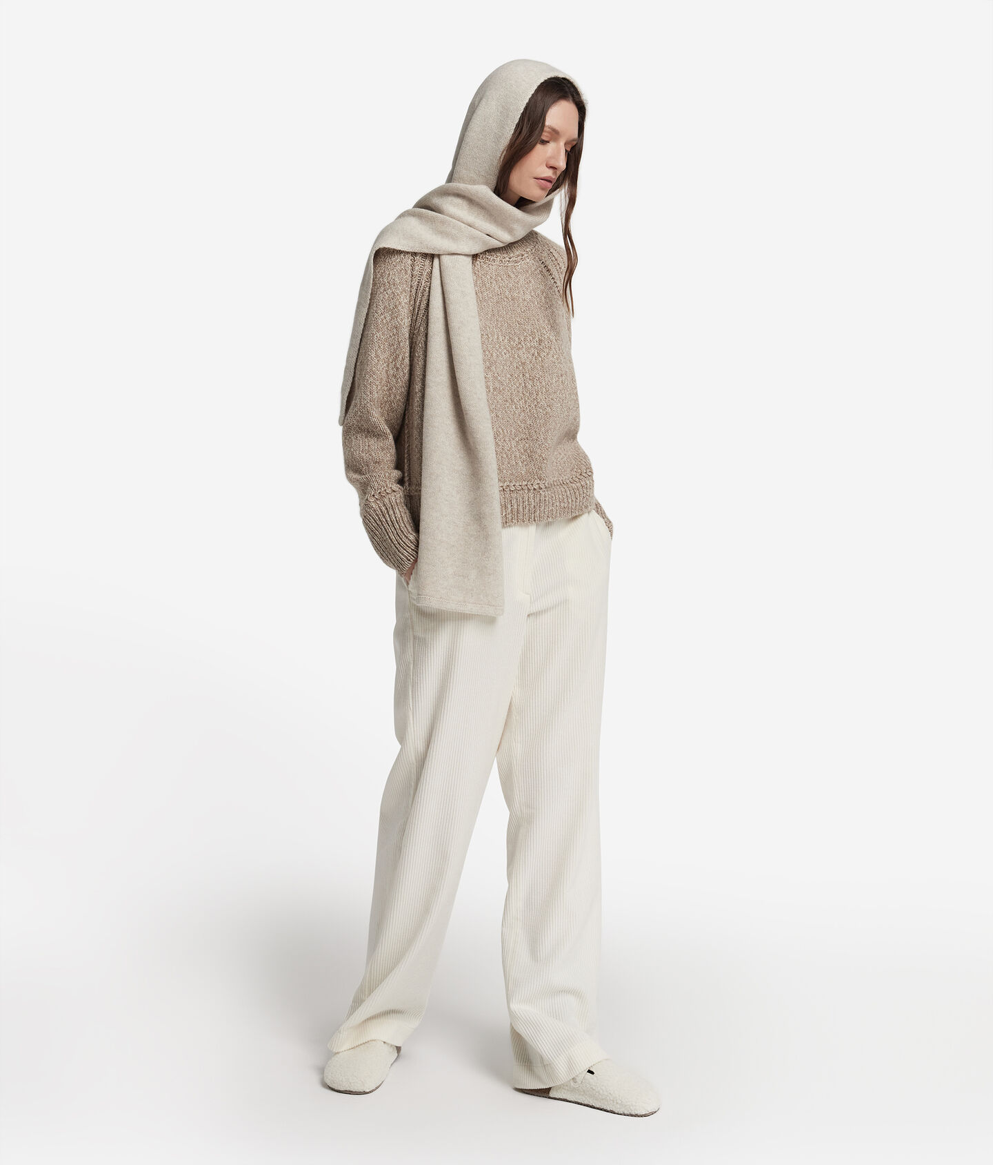 Woman wearing a cream hooded knit scarf with a beige sweater and cream wide-leg trousers