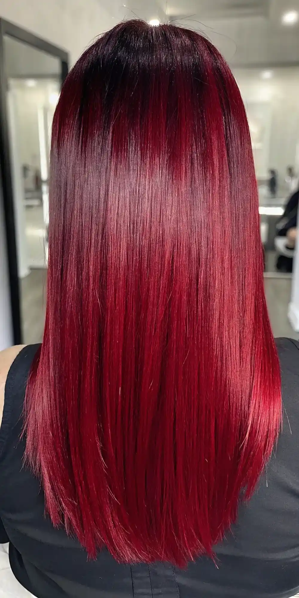 Back view of long straight hair with dark root shadow melting into cherry red lengths