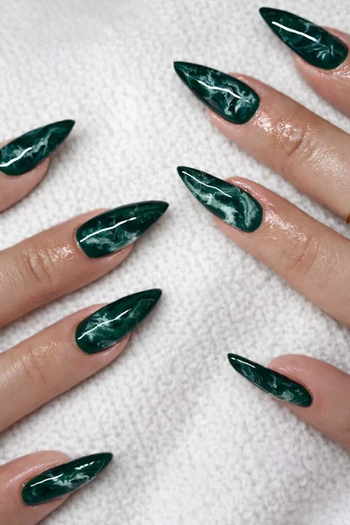 Long stiletto nails in dark emerald marble with white swirls