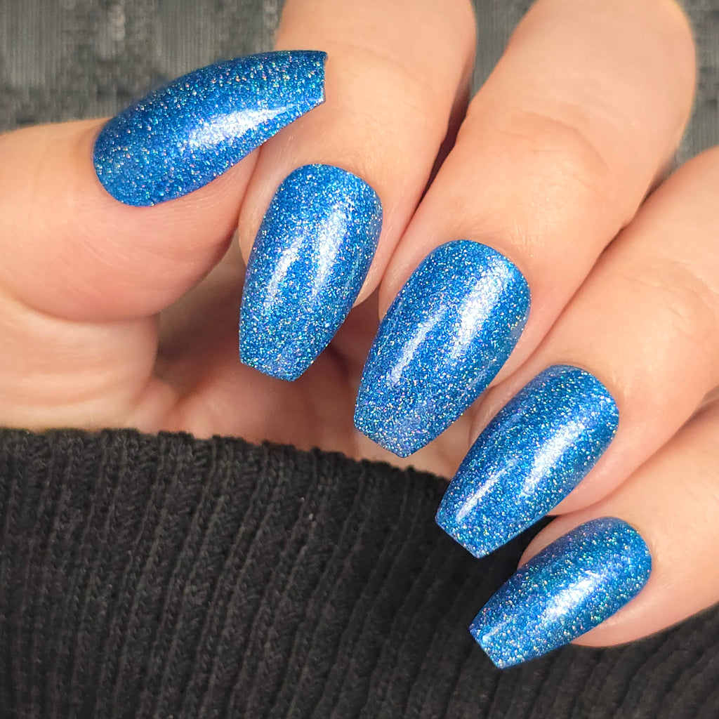Short oval nails covered in icy blue holographic glitter