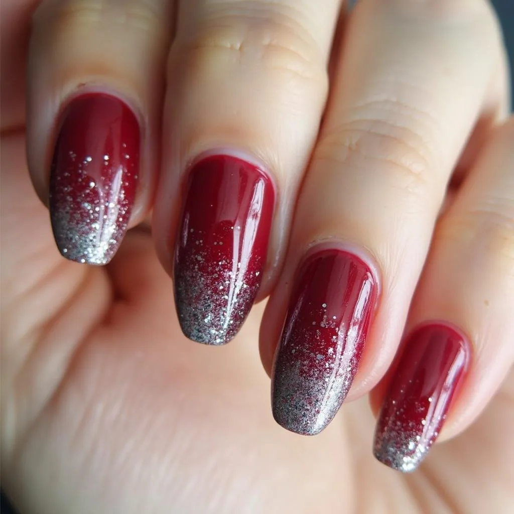 Almond nails in deep cranberry red with silver glitter gradient toward the tips