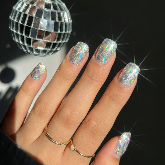 Short squoval nails fully covered in chunky iridescent holographic glitter