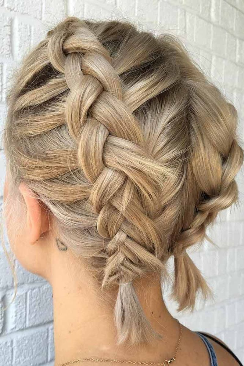 Blonde double dutch braids feeding into a low bun at the nape