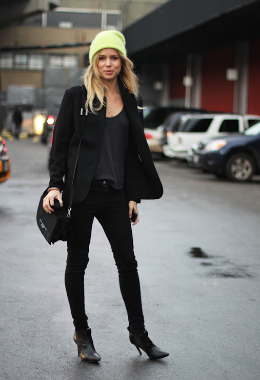Woman in a neon green beanie and all-black outfit with heeled boots