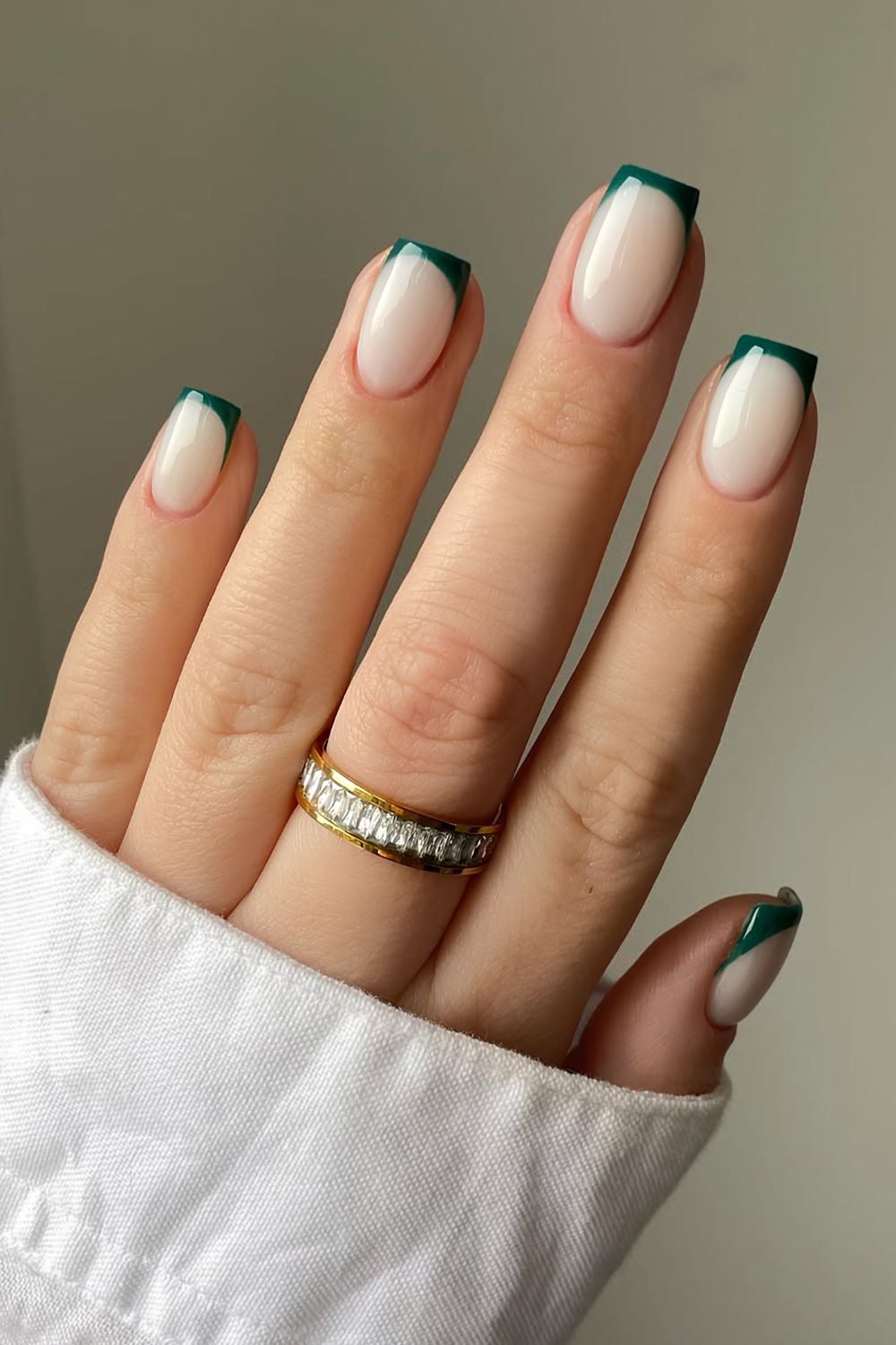 Emerald green French tip nails on a milky nude base