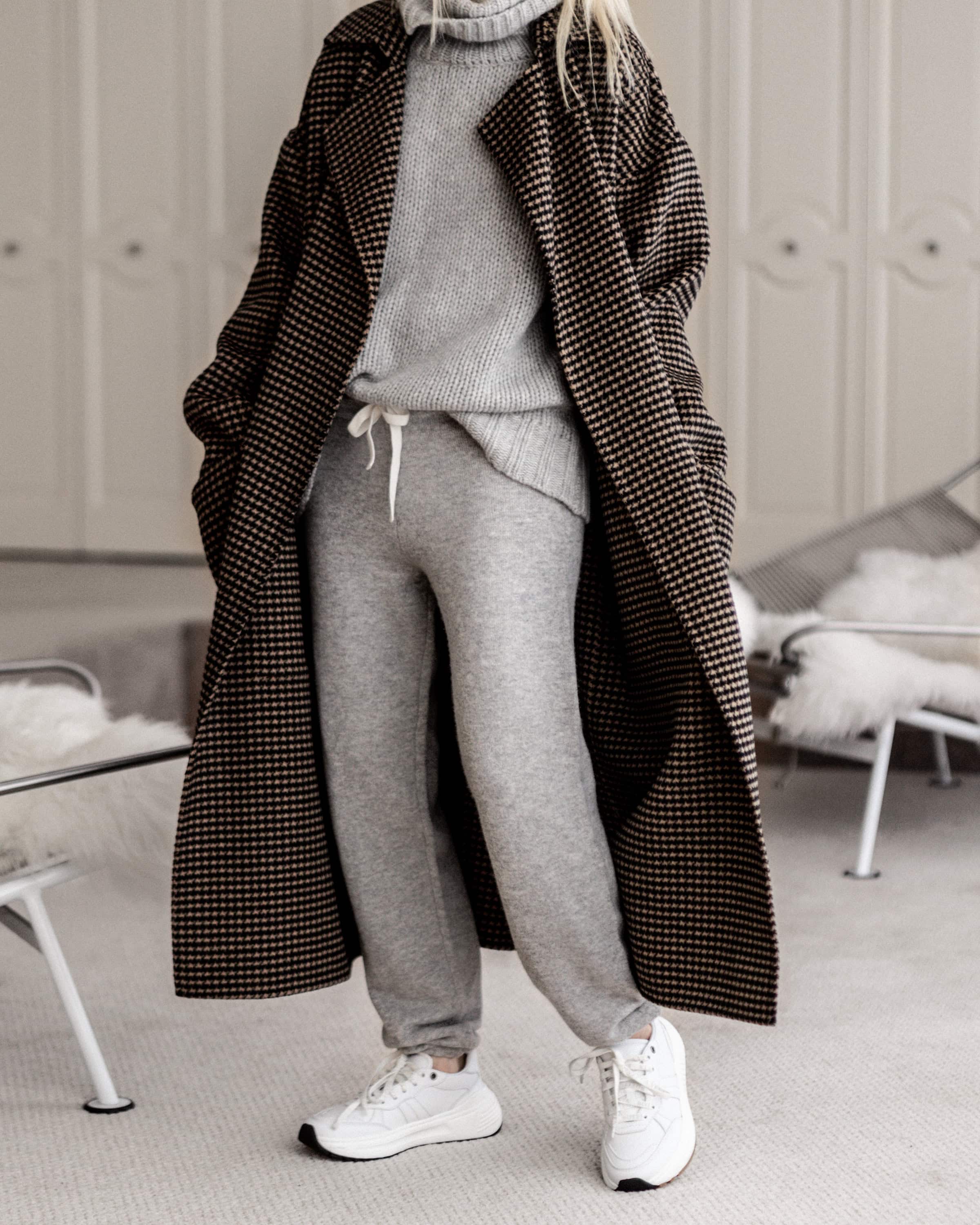 Woman in a cozy winter outfit of sweatpants with a long coat from a shop-the-look feature