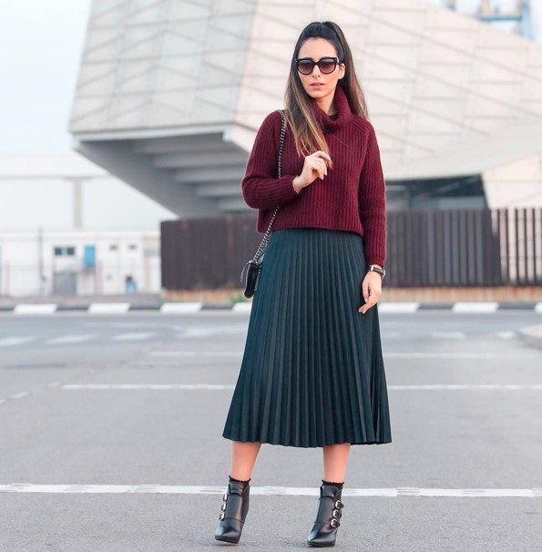 Woman in black buckled ankle boots, burgundy turtleneck sweater and dark pleated midi skirt
