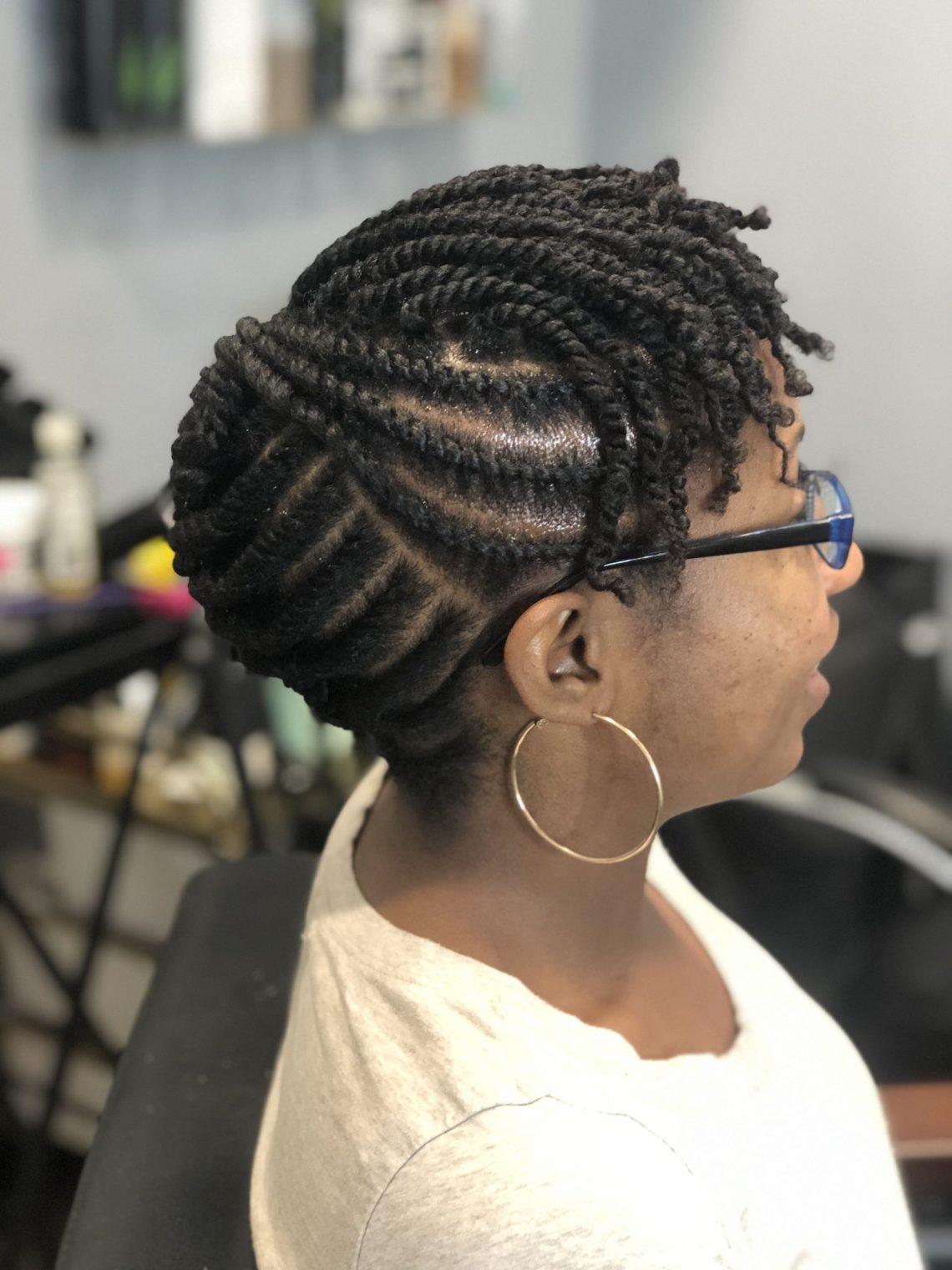 Flat twists swept back and pinned into a low tucked bun with loose twist ends