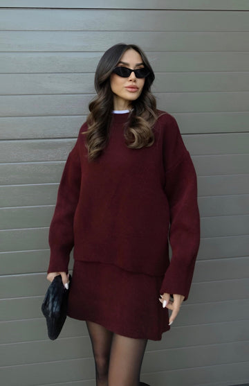 Woman in a burgundy knit sweater and matching mini skirt with sunglasses