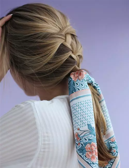 French braid into a low ponytail with a teal floral scarf wrapped around its base