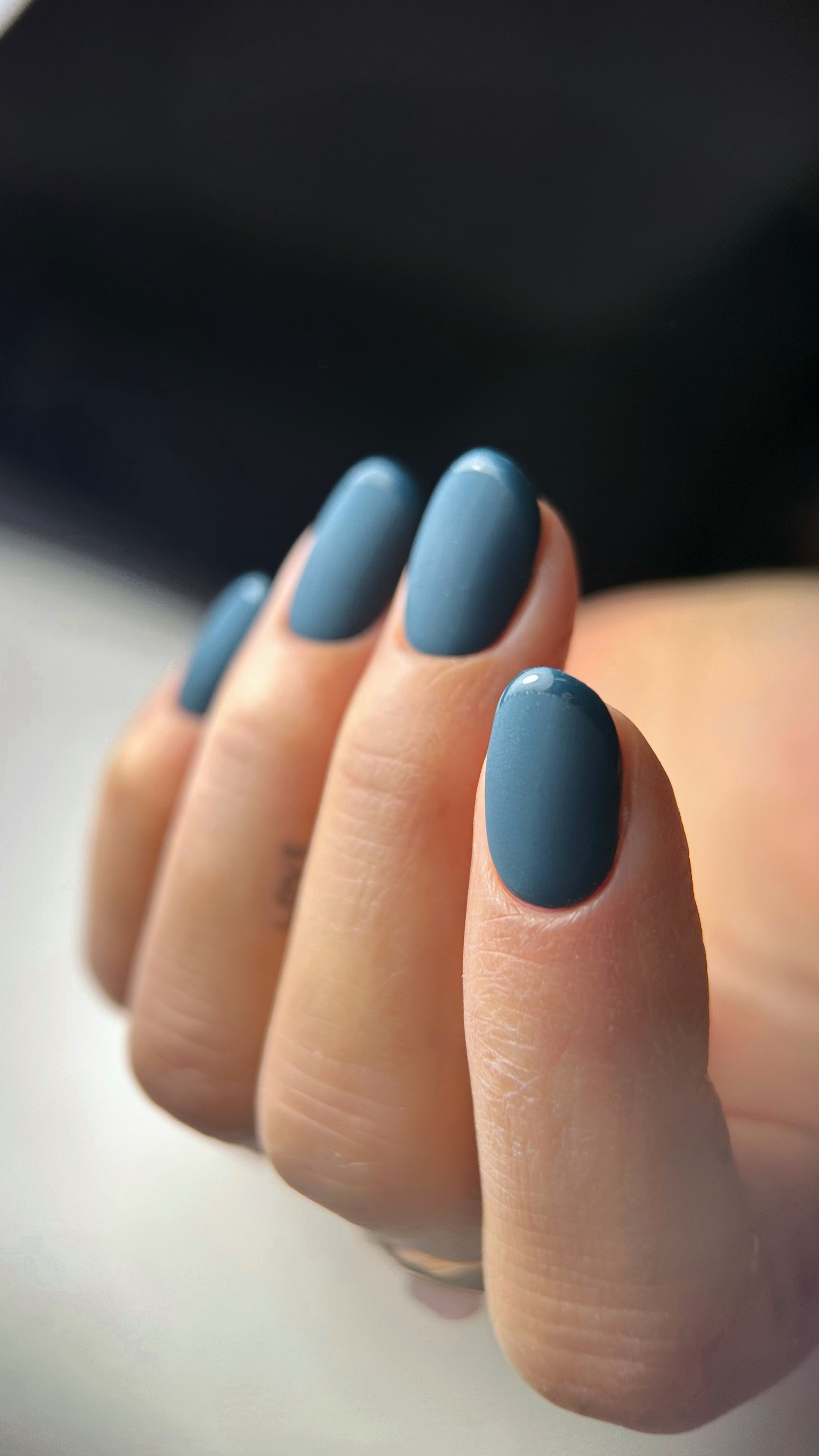 Short nails in muted slate blue with a flat matte finish