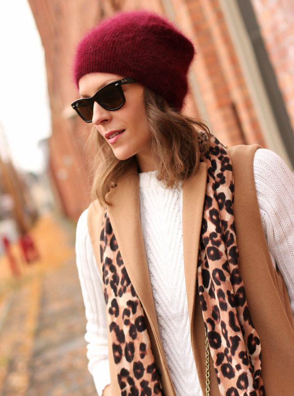 Woman in a magenta fuzzy beanie, leopard scarf and camel vest
